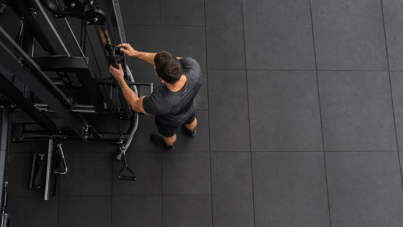 Man adjusting a cable handle in a quiet gym, viewed from overhead